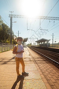 穿着T恤衫 牛仔裤和医疗面具等待火车的小女孩女孩安全保健隔离孩子感染铁路疾病车站乘客图片