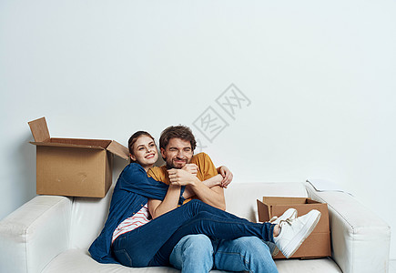 男女拥抱男男女女坐在白色沙发上 房间里装着一箱东西工具在移动闲暇拥抱浪漫幸福男性成人房子家庭女士控制背景