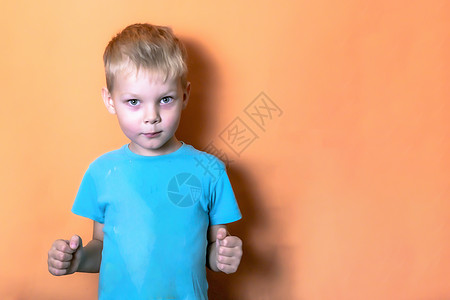 5 -7岁男孩穿着蓝色T恤 在粉红背景上 看镜头镜头紧紧握着拳头图片