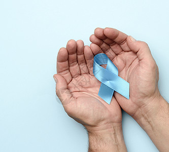 雄性手握着蓝丝丝带 以圆形的浮云为形状蓝色癌症疾病男人幸存者丝带药品卫生机构医疗图片