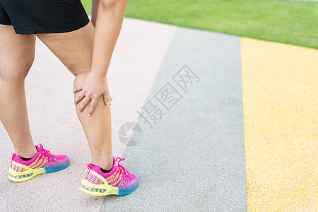 女性胖脚步运动员腿部受伤和疼痛 手抓着痛苦的腿在公园里跑来跑去按摩膝盖十字形小牛女士慢跑者跑步伤害事故训练背景图片