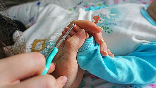 新生儿的指甲用剪刀切开母亲微距卫生身体妈妈手指男生父母宏观新生图片