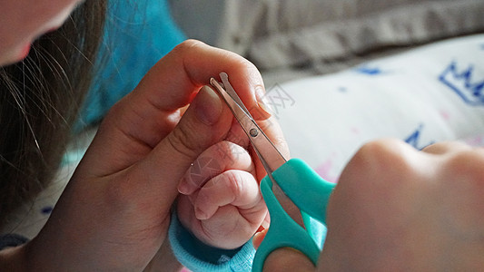 新生儿的指甲用剪刀切开父母新生孩子宏观母亲药品摄影女士皮肤妈妈图片