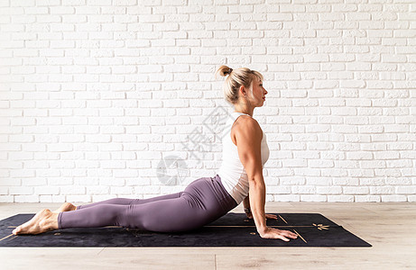 年轻有吸引力的妇女从事瑜伽 穿运动服 白衬衫和紫裤子 室内长整身 灰色背景健身房训练体操姿势女孩哈达肌肉爱好身体活动图片