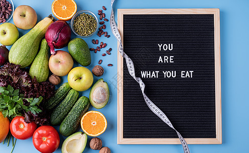 新鲜蔬菜和水果 用于健康饮食 测量胶带和黑纸板 上面写着“你是什么就吃什么”的字眼图片
