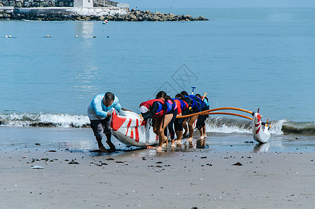 一群儿童在夏日将船拖向岸边的划船者图片