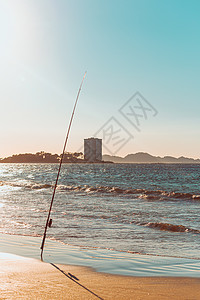 在西班牙日落时在一栋大型建筑前的海滩上钓鱼棒海浪摄影白色娱乐游戏铸件比赛休闲冲浪太阳图片