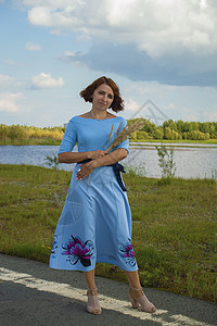 穿着蓝色裙子的女士带着花束 站在路边与绿河对峙伴娘花朵庆典婚礼新娘幸福婚姻成人女孩订婚图片