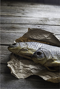 以木制背景的折叠手纸上的盐咸干鱼Vobla营养尾巴海鲜啤酒酒吧美食小吃午餐淡水咸鱼图片