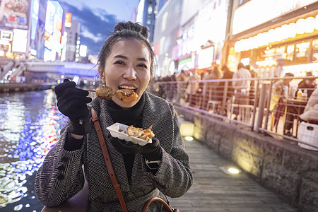 年轻女游客在Stre散步时 享受街头食物油炸章鱼餐厅街道文化烹饪运河女士旅行美食图片