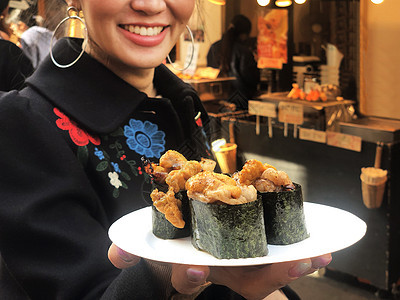 观光女游客展示牛肉寿司 最流行的美味食品店铺旅行蔬菜街道扇贝烹饪盘子海洋女士市场图片