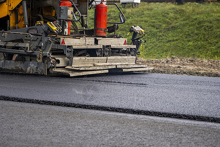 在道路建设工地铺设新鲜沥青的工业沥青帆机建筑运输碎石活动车辆柏油苦工车道路面劳动者图片