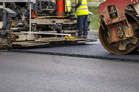 在道路建设工地铺设新鲜沥青的工业沥青帆机维修振动器柏油活动苦工卡车蒸汽平板车辆劳动者图片