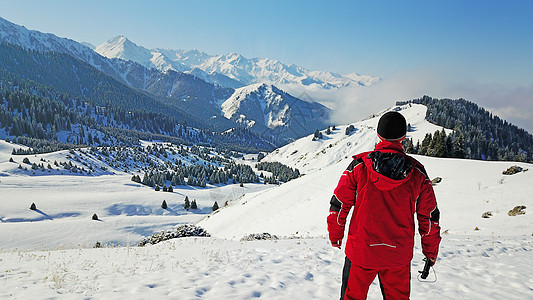 那家伙看着雪山和云彩旅游岩石背包森林全景顶峰冒险套装丘陵晴天图片