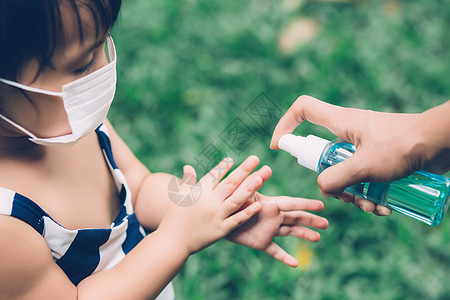 母亲在户外用面罩和消毒剂照顾儿子 以保护流感或 covid19 母亲和孩子戴着医用面具清洁手 以确保在公共场合爆发大流行病的安全图片