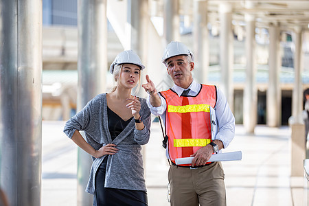 土木工程 建筑工程师在建筑工地或高层建筑工地与建筑师讨论 并进行轮廓规划测量安全工人办公室男性头盔会议项目职业经理咨询图片