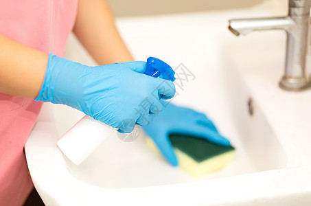 人 手放在照片中的蓝色橡胶手套上 清除和洗浴室水槽背景图片