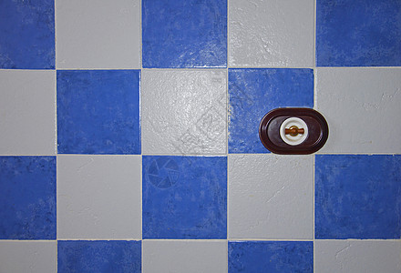 蓝色和白色瓷砖墙上的棕色灯开关图片