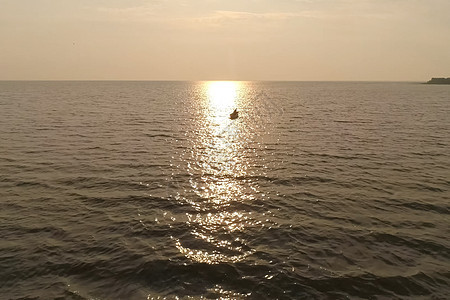 渔民在海上的一条船上 与日落相对应蓝色运输渔船黄金渔夫旅行海岸海洋地平线反射图片