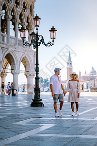 一对夫妇在威尼斯进行城市旅行 欣赏圣马可广场 意大利威尼斯总督府公爵宫的景色 威尼斯的建筑和地标 威尼斯的日出城市景观历史性街道背景图片