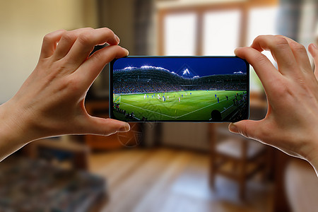 在家通过智能手机观看足球比赛 在体育场播放足球赛 笑声视频屏幕手表网络房间娱乐电视团体居住运动图片