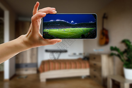 在家通过智能手机观看足球比赛 在体育场播放足球赛 笑声团体播送渠道娱乐长椅细胞居住游戏展示电视图片