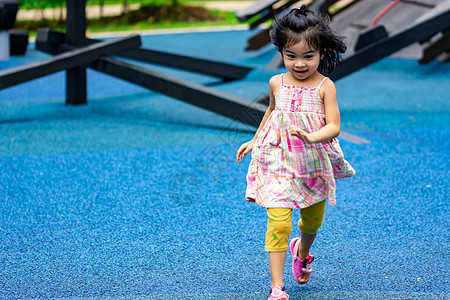 在游乐场上跑跑跑玩耍时 可爱的小女孩乐趣金发女孩女性金发女郎阴影裙子绿色场地童年图片