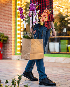 男子在摩托兰花内拿着购物袋行走图片