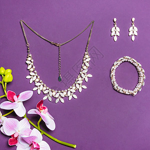 珠宝盒高级金项链手镯和耳环 带有钻石的紫色背景背景