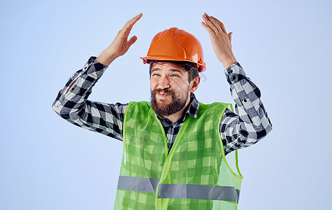 穿着硬帽子的情感建筑师 和反感怜悯的姿态 他的双手在蓝背景上男人帽子工人职业安全帽承包商工作建造头盔安全图片