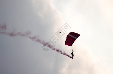 在空中展览期间 剪影降落伞特技在空中滑行时没有聚焦和模糊 带着红色的烟雾痕迹天空风险活动橙子空气日落飞机烟迹危险红烟图片