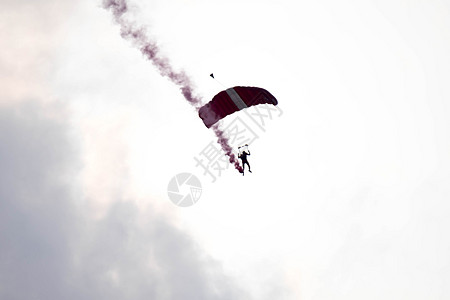 在空中展览期间 剪影降落伞特技在空中滑行时没有聚焦和模糊 带着红色的烟雾痕迹男人运动橙子日落天空危险飞机红烟空气自由图片