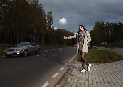 身着灰色大衣的年轻女孩站在路边 试图拦车女士丝袜冒险帮助自由外套汽车成人运输假期图片