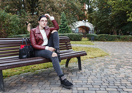 坐在公园长椅上的女孩女性季节快乐眼镜黑色成人黑发休息棕色牛仔裤图片