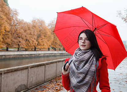 配雨伞的年轻女孩肖像下雨女士黄色树叶公园天气外套季节胡同红色图片