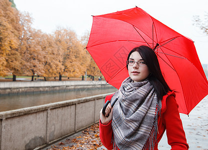 配雨伞的年轻女孩肖像女士天气红色胡同黄色公园树叶季节外套下雨图片