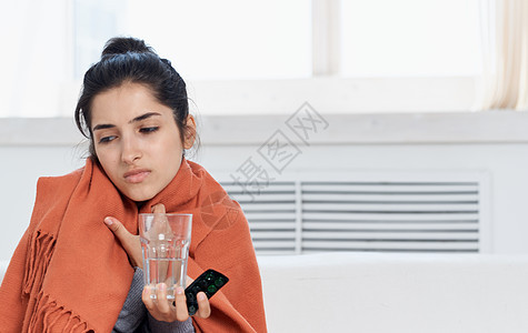 身穿橙色格子 手掌中装着玻璃杯的妇女有过敏性健康问题图片