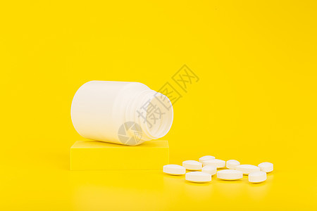 在讲台上的白药瓶上 在黄色背景和复制空间下洒出蛋黄丸子图片
