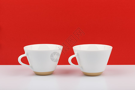 红色背景下白桌上的两个白色陶瓷咖啡杯 有 tex 空间图片