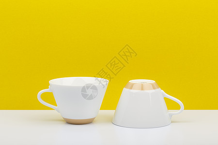 白桌上两个白色陶瓷咖啡杯 以亮黄色背景和文字空间为蓝色;图片