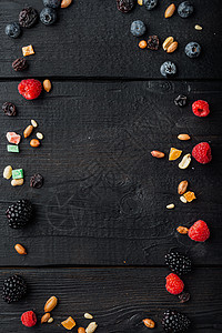 由混合干燥和生熟莓果和水果 坚果 带复制空间的顶视图 黑木制桌图片