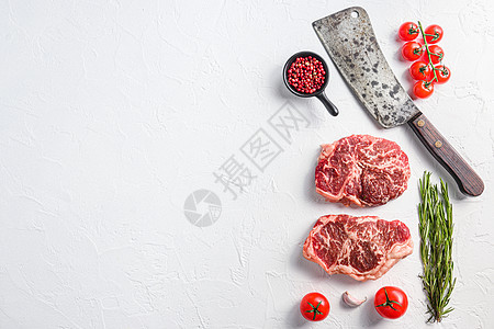 生顶级牛排 带调味料的有机肉 迷迭香和切肉刀 白色带纹理的背景 带有文本空间的顶视图图片