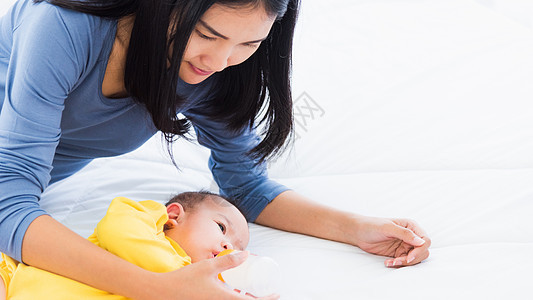 母亲用奶瓶喂养和抚养婴儿的新生婴儿女性厨房婴儿床椅子牛奶瓶子保姆家庭父母投标图片