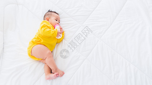 婴儿中含奶瓶的婴儿说谎女孩公式新生食物家庭房间衣服女儿卧室图片