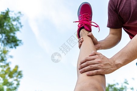 男性在运动受伤后用手抓住女性腿伸展肌肉健康赛跑者活动训练鞋类运动员耐力慢跑者运动装图片
