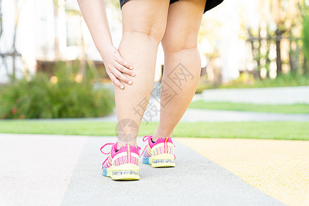 女性胖脚步运动员腿部受伤和疼痛 手抓着痛苦的腿在公园里跑来跑去肌肉事故训练伤害十字形跑步按摩治疗慢跑者膝盖图片