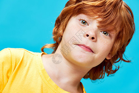红头发有雀斑的红发男孩 面对近身蓝色背景工作室图片