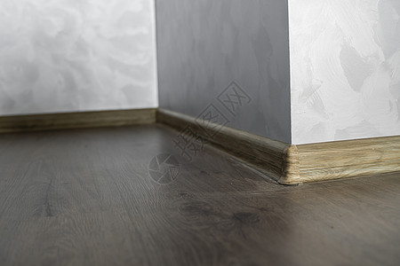与具有木质纹理的塑料底板层压 家里新安装的强化木地板和踢脚板 现代设计 深色橡木地板镶木地板上塑料底座的特写角落压板地面控制板房图片