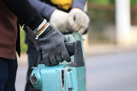 男性工人使用电动混凝土破碎机在当地城市道路 人行道 工作施工现场用手提钻挖掘和钻孔混凝土修复车道表面岩石工程破坏铺路男人石匠劳动图片