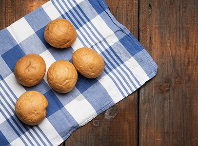 在棕色木制桌子上烤圆小面包包小麦糕点面包圆形白色营养蓝色食物午餐包子图片